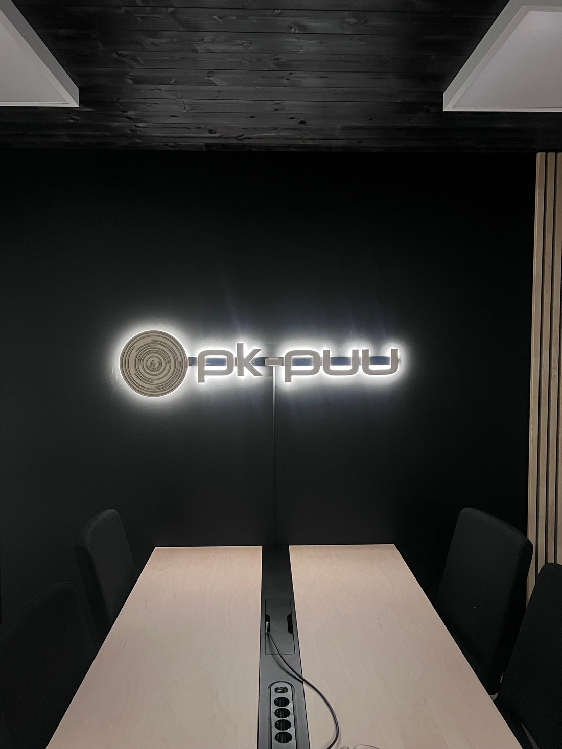 Valaistu logo vanerista PK-Puun neuvotteluhuoneeseen